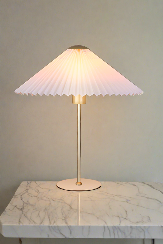 Table lamp with a pleated shade placed on a marbletable