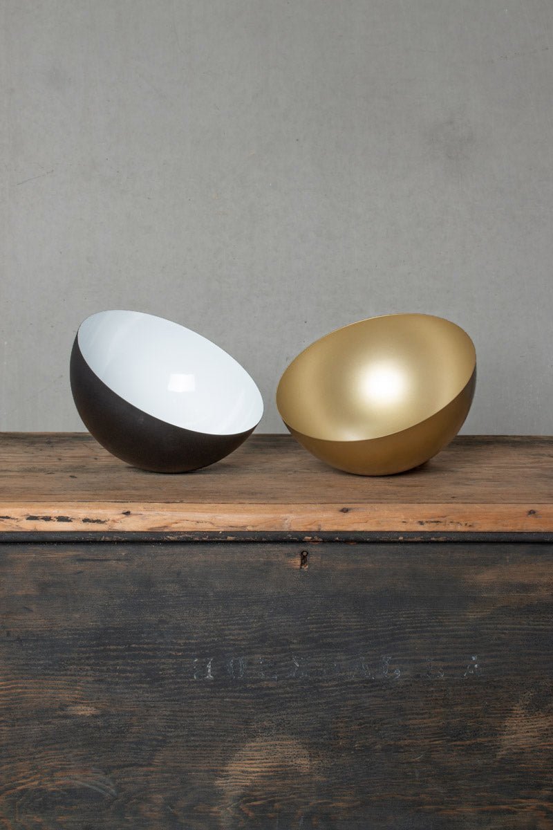 Image of the small Dome shades upside down on a bench in gold/brass and black. 