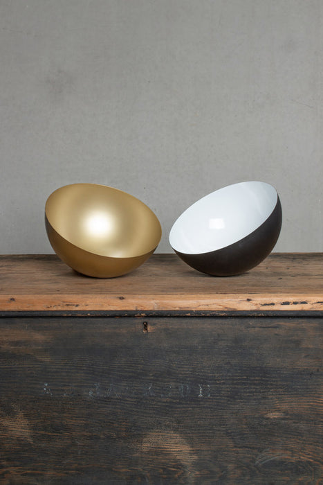 Image of the small Dome shades upside down on a bench in gold/brass and black. 