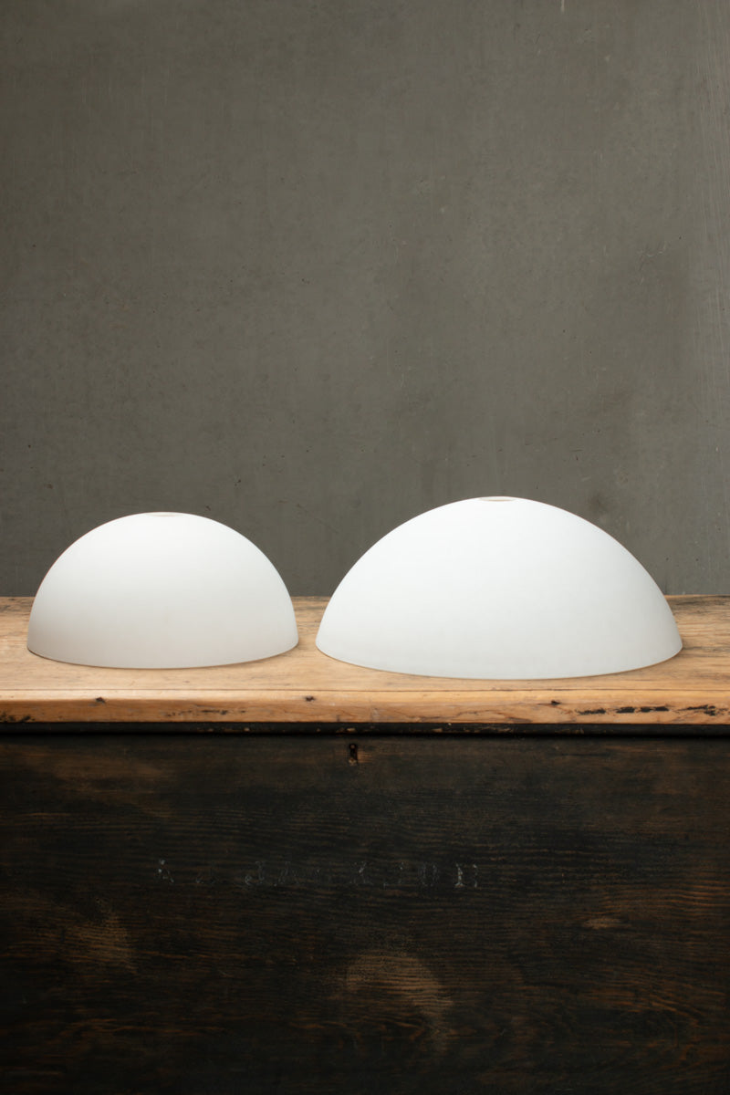 Small and large opal dome shades sitting on a timber bench.