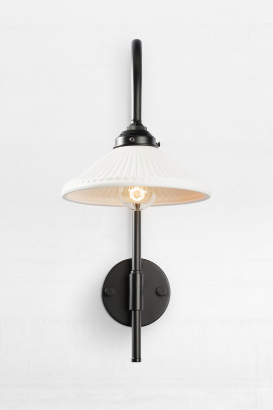 Front on view of the Shepard gooseneck wall light in black with a matt white ceramic shade. 