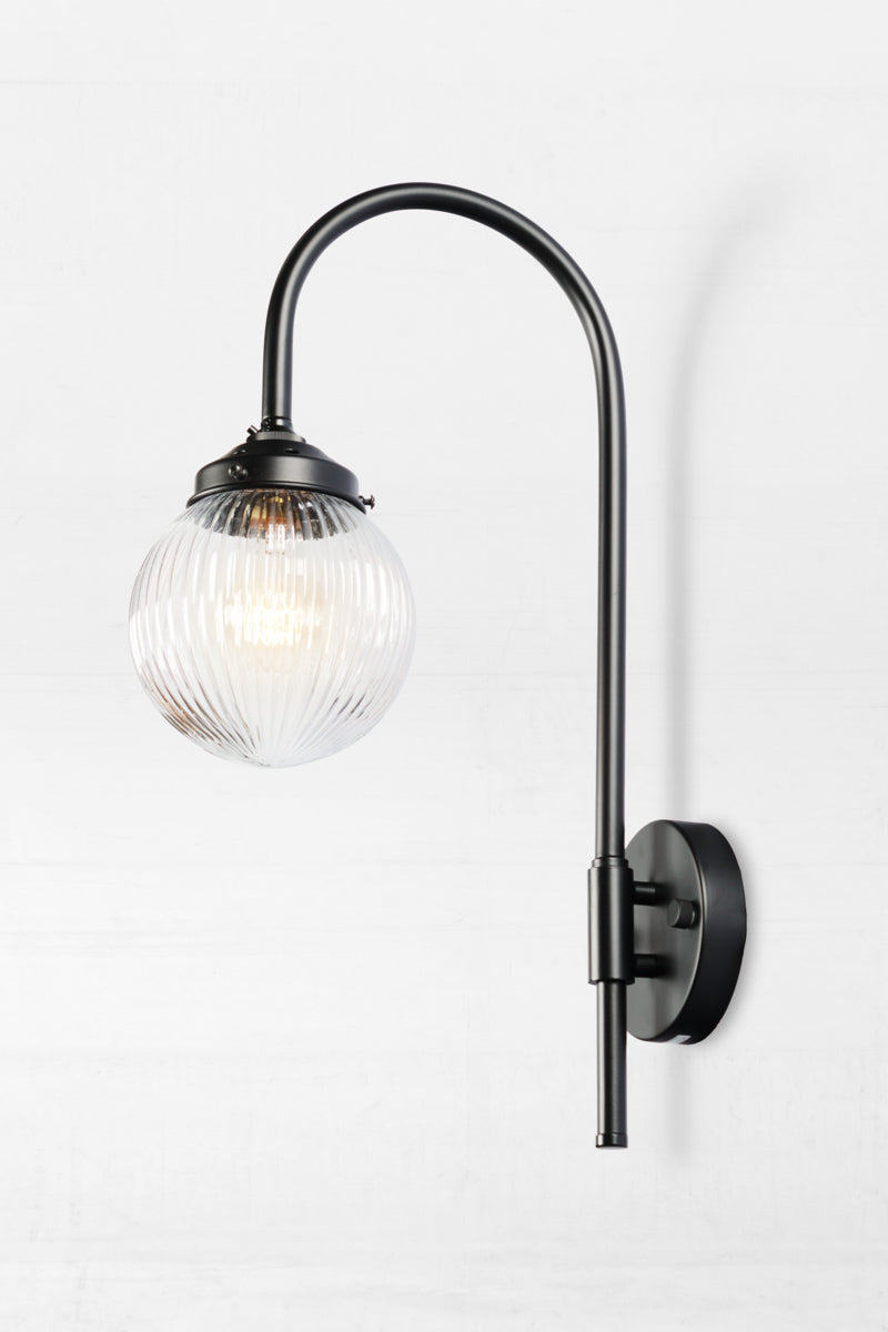 Shepard gooseneck wall light in black with a clear reeded glass ball shade. 