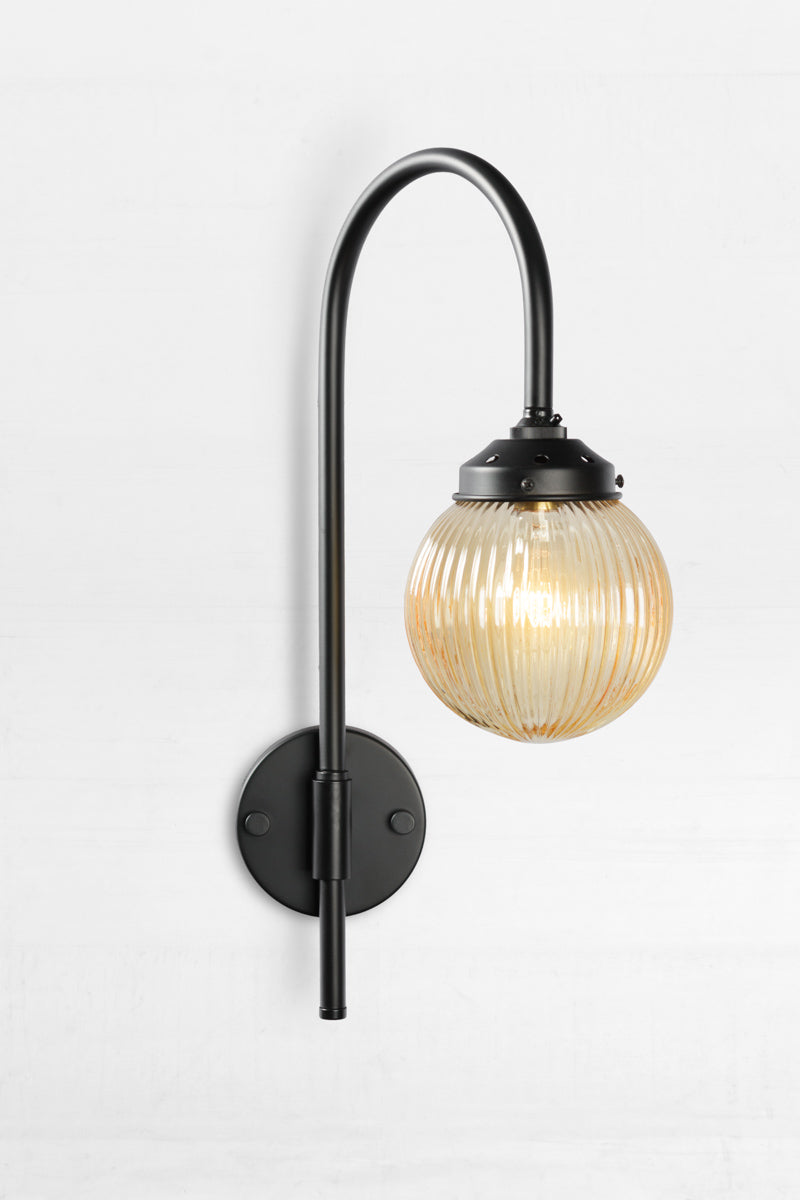 Shepard gooseneck wall light in black with an amber reeded glass ball shade. 