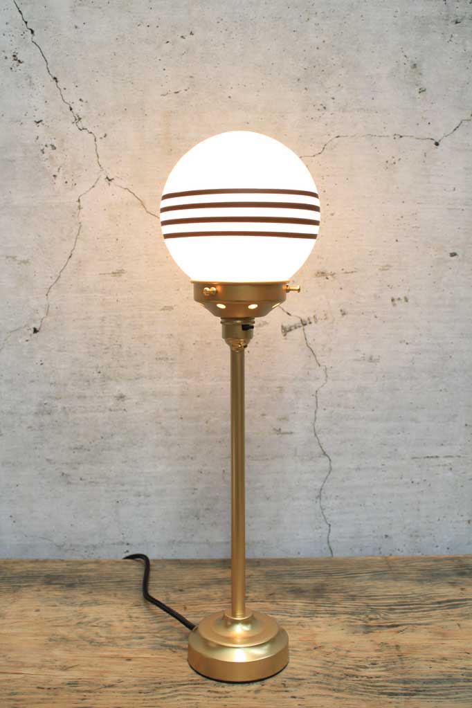 Gold candle stick table lamp with an opal shade with four stripes.