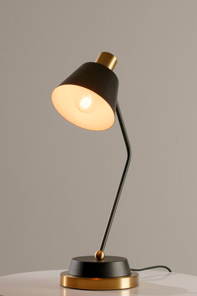 Side angle of the Cine Table Lamp highlighting its matte black shade and gold accents.