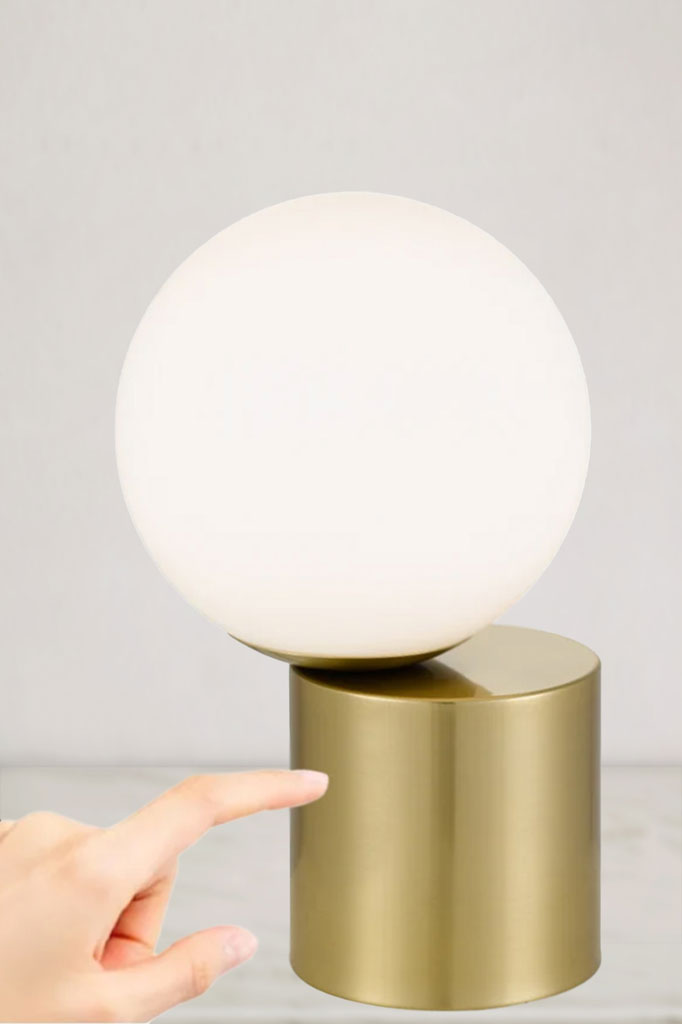 Off centred opal ball shade on a gold cylindrical touch lamp base.