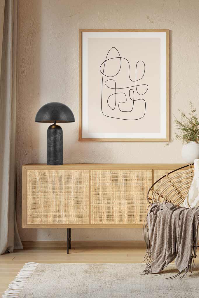 A large Newman Table Lamp in black on a sideboard of a beige toned sitting nook. 