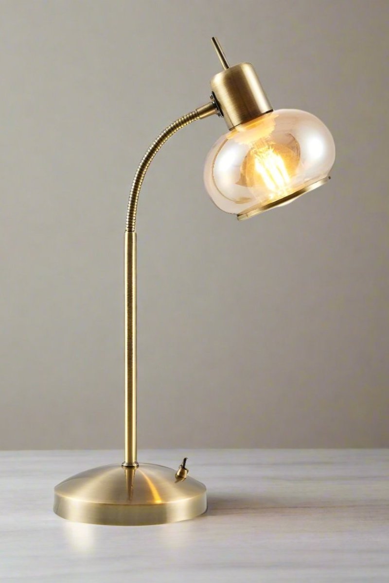 Side view of a Manhattan table lamp in antique brass on a marble table