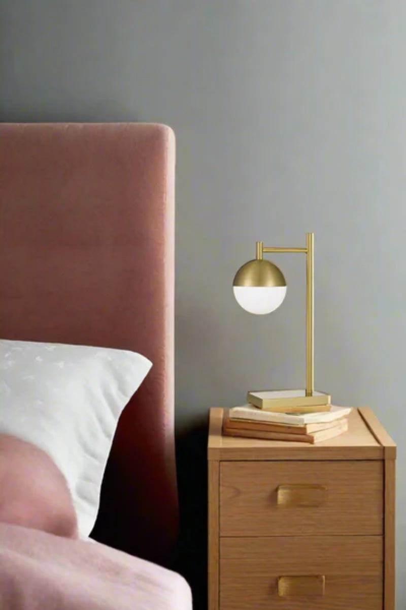 Gold crown sphere hook table lamp on a bedside table
