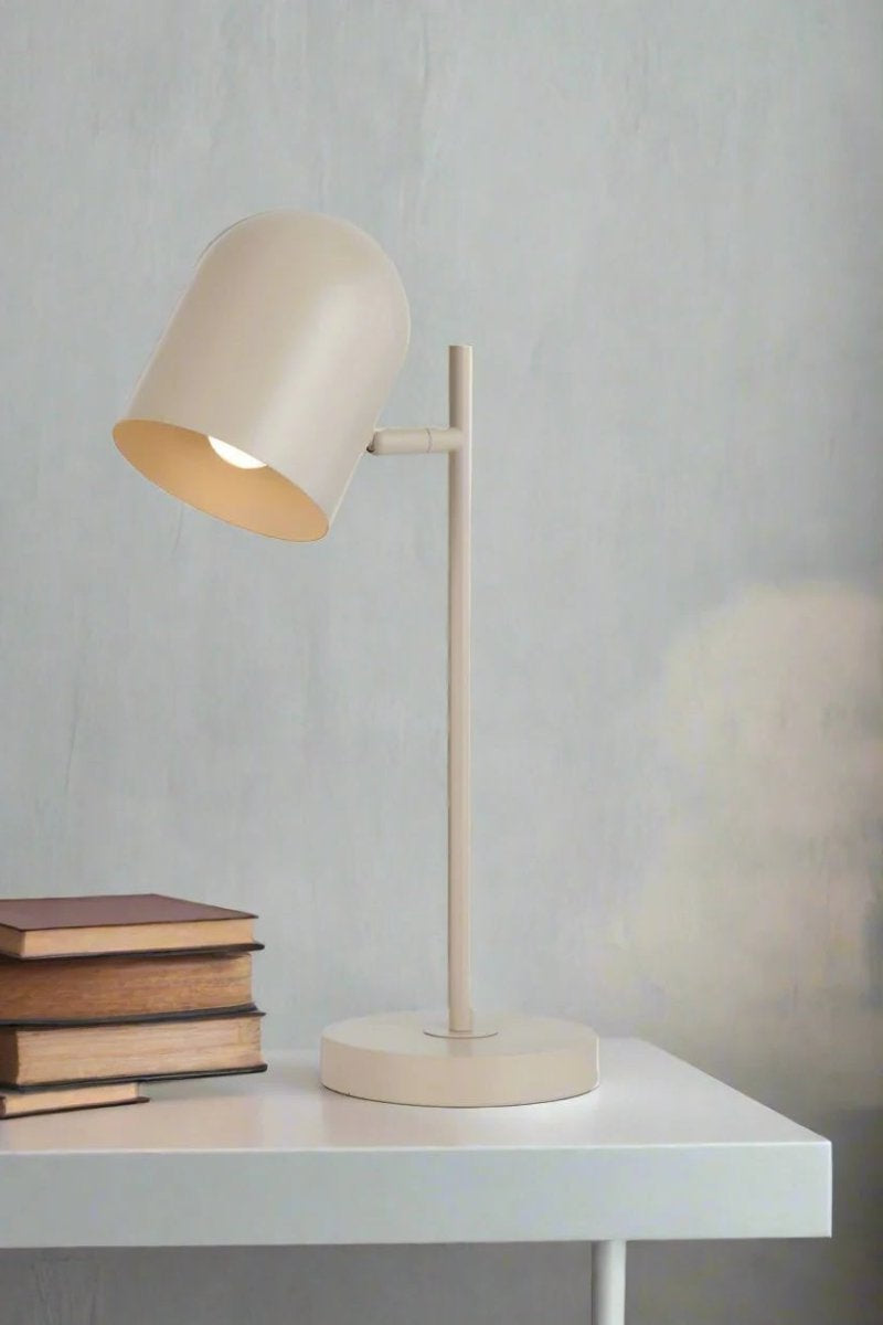 Khaki table lamp with adjustable head next to some books. 