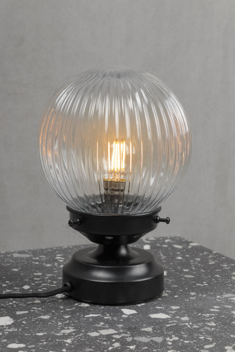 Close view of the Clear reeded glass ball lamp with a black base. 