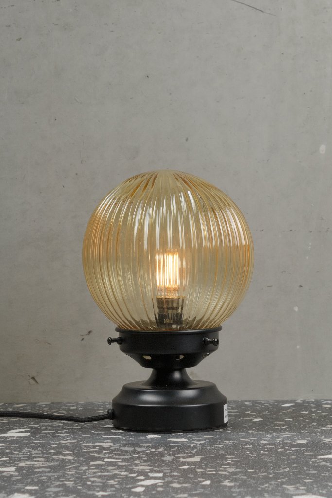 Amber reeded glass ball lamp with a black base. 