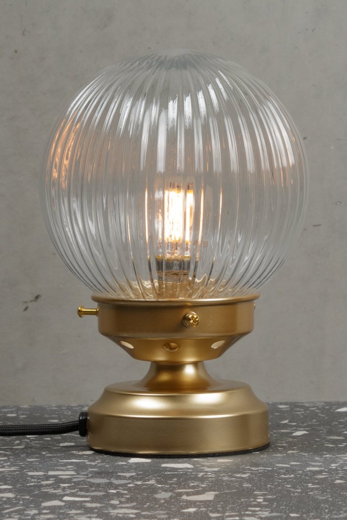 Clear reeded glass ball lamp with a gold/brass base. 