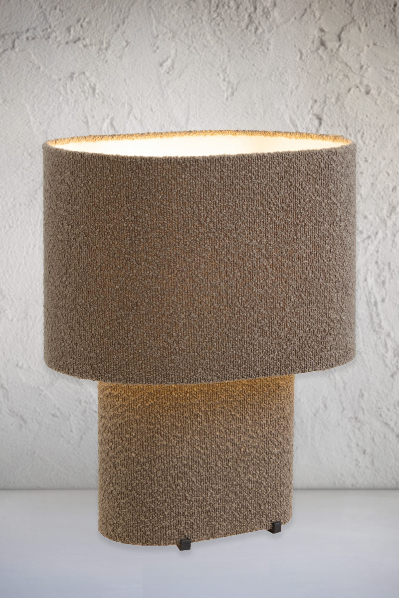 Brown broulee fabric table lampwith the light on.