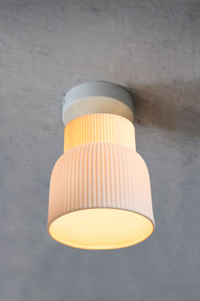 Pleated ceramic shade, flush mount on a white ceiling batten. 