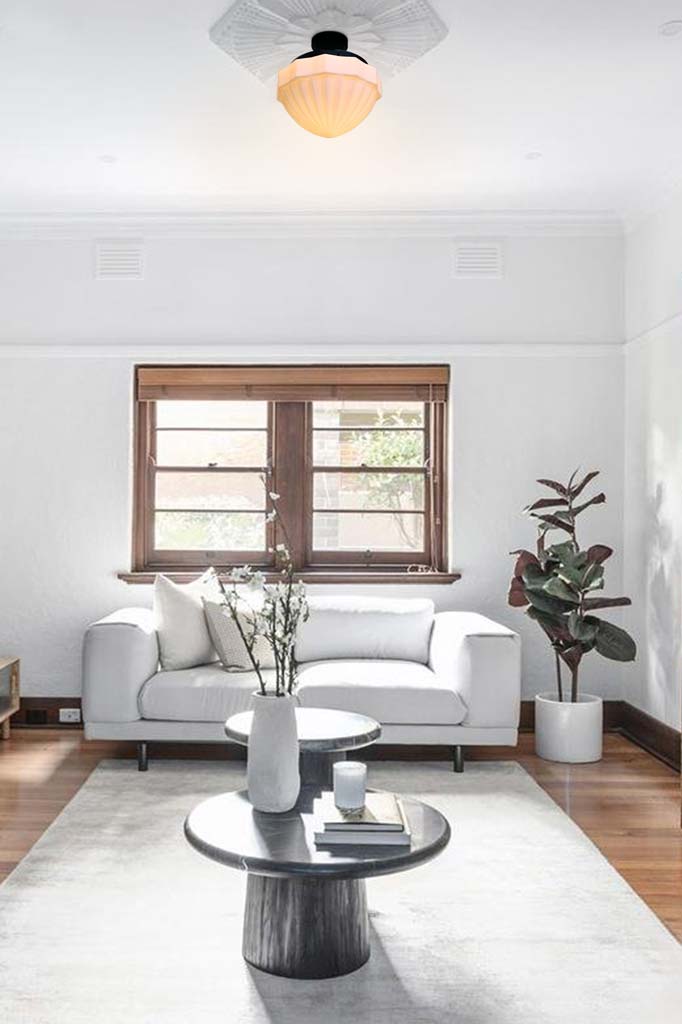 Bright lounge room with couch and coffee table. Vintage light hanging from ceiling rose