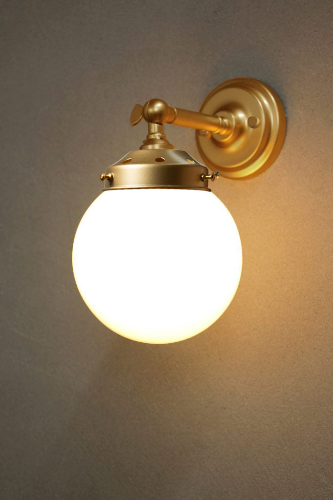 Small opal glass ball shade on a short gold/brss wall sconce