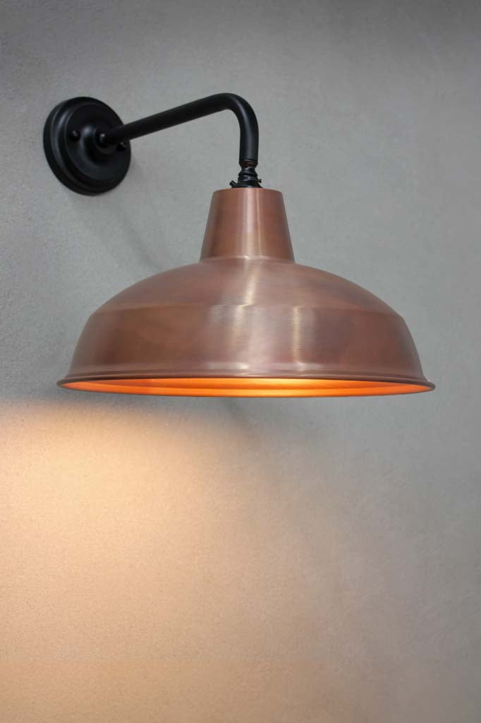 Aged solid copper warehouse shade on a black steel sconce.