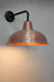 Aged solid copper warehouse shade on a black steel sconce.