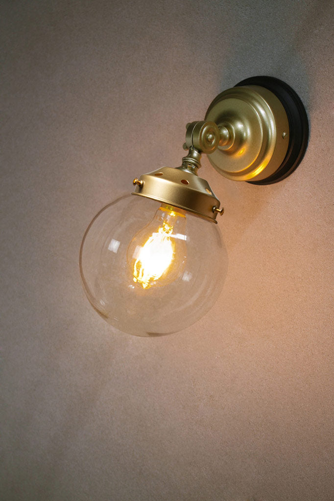 Small clear glass ball shade on a gold/brass wall sconce