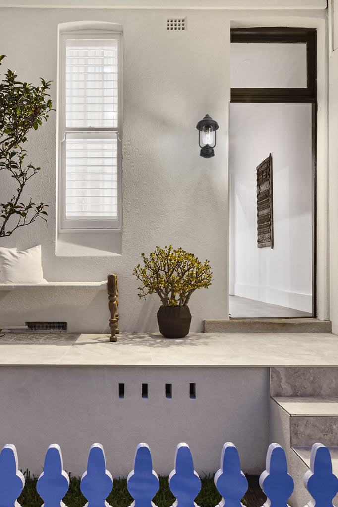 Antique Bronze finishes outdoor wall light on a front porch of a white washed house. 