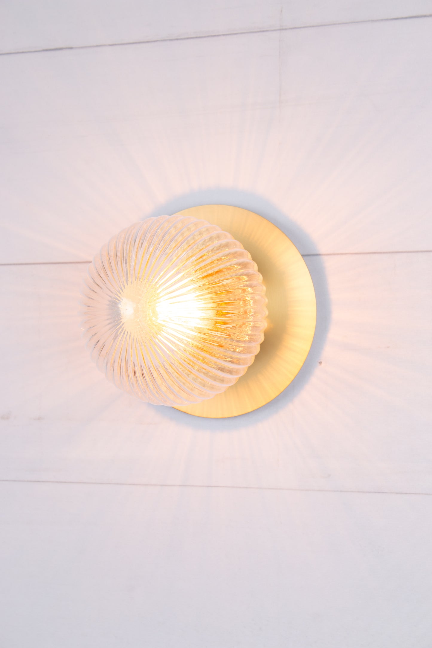 Small clear reeded glass ball shade paired with a small brass disc. 