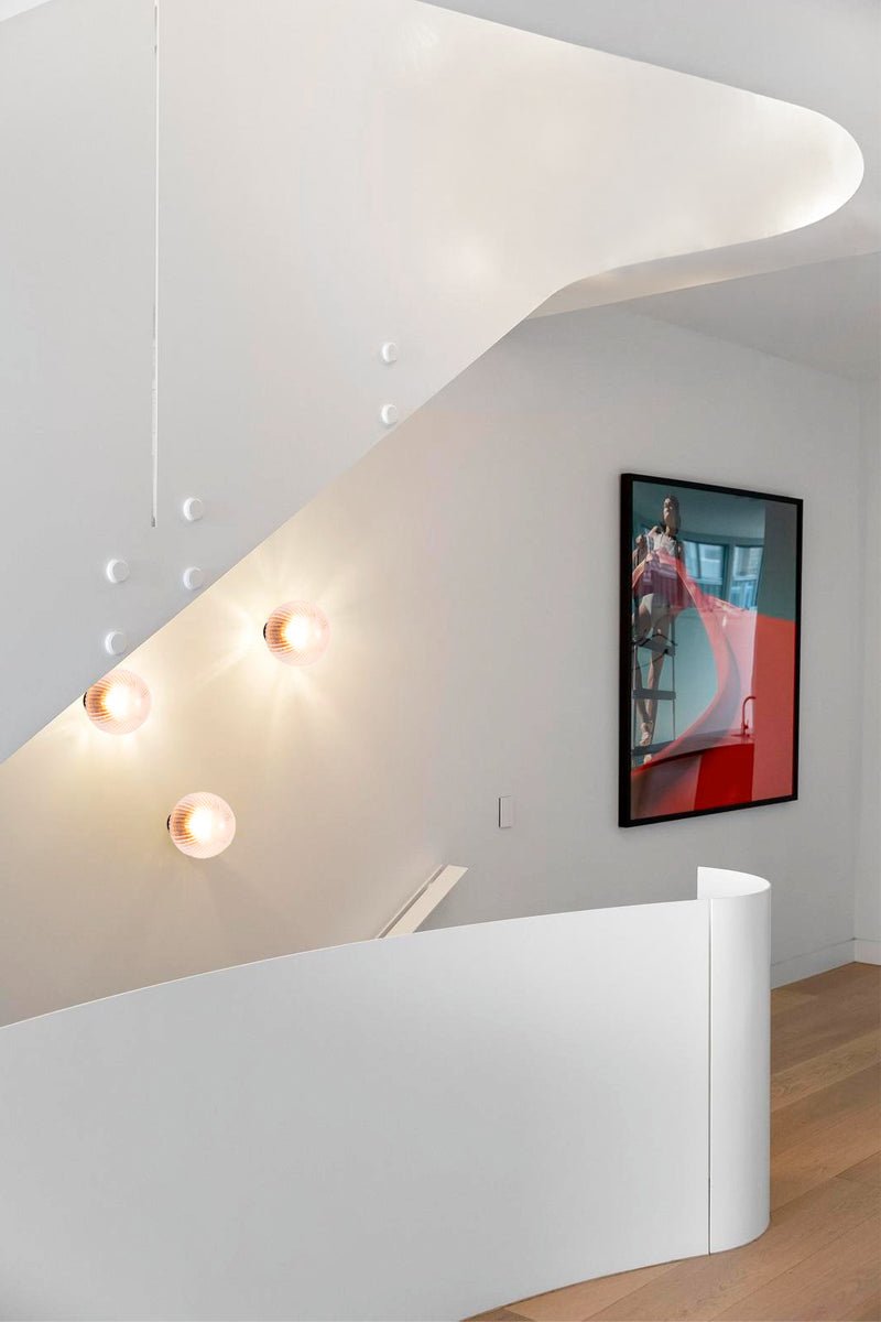 Three dakota reeded clear class wall lights at the top of a modern home staircase. 