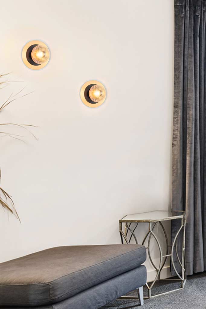 Two amber reeded clear glass ball lights with a small black disc and a large brass disc detail in an entryway. 