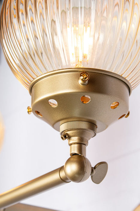 gold brass arm sconce with detailing of amber shade