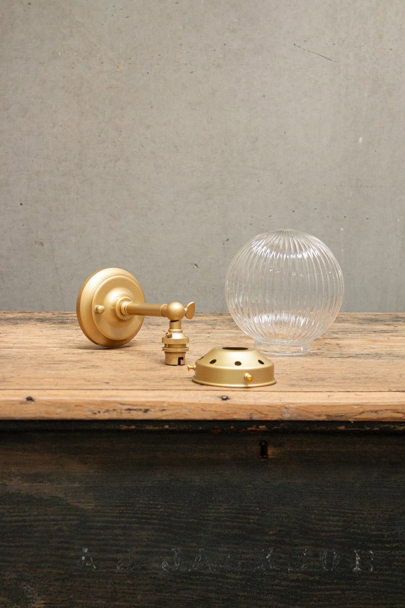 Disassembled clear reeded glass ball light with gold/brass gallery and short straight arm. 