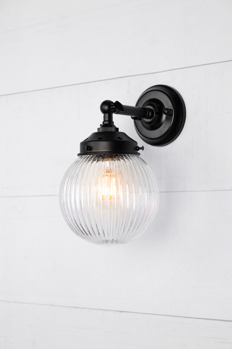 Clear glass reeded ball shade on a short black swivel straight arm.