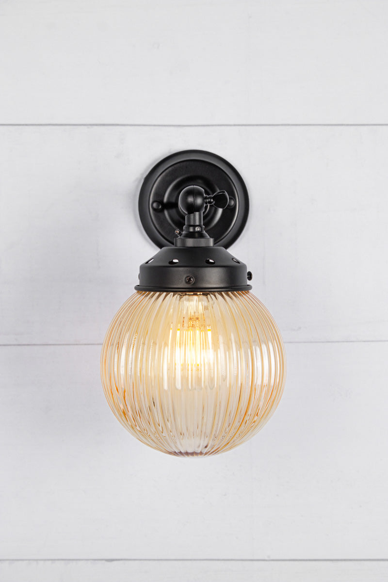 Amber glass reeded ball shade on a short black swivel straight arm.