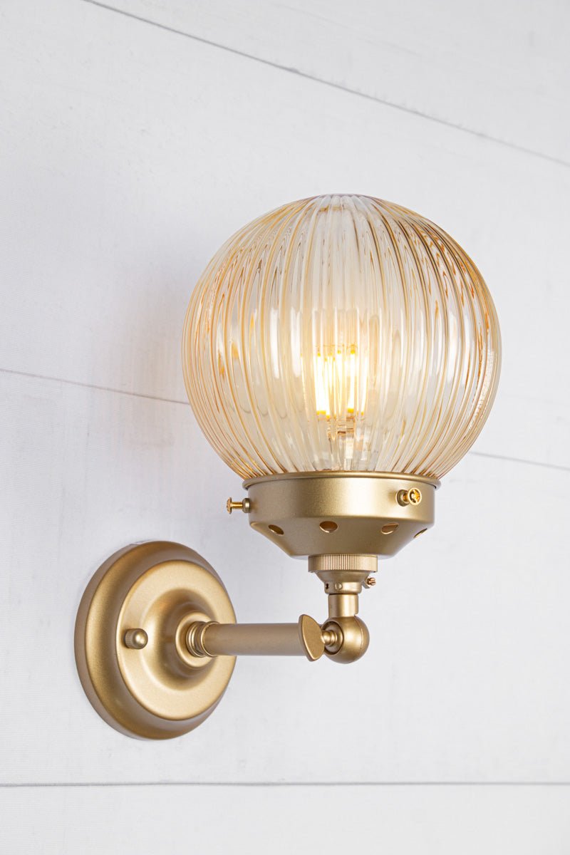 Amber glass reeded ball shade on a short gold/brass swivel straight arm.