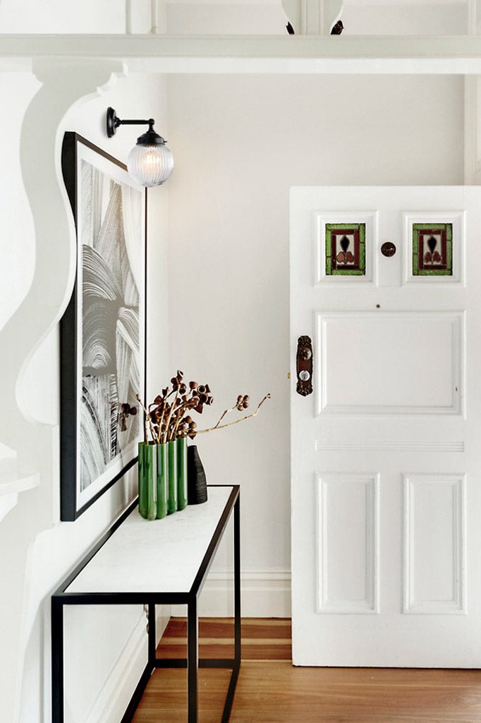 Clear reeded glass ball shade on a black straight arm sconce in an entrance way