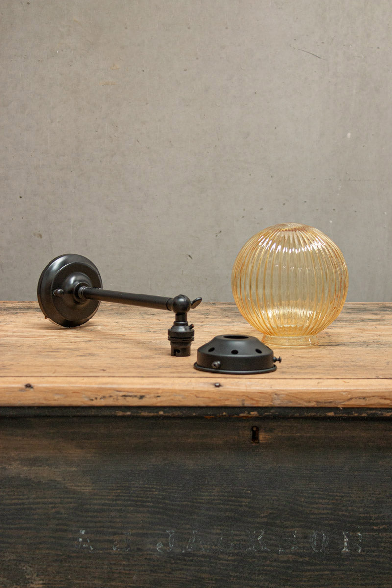 Disassembled Amber reeded glass ball light with black gallery and long straight arm. 