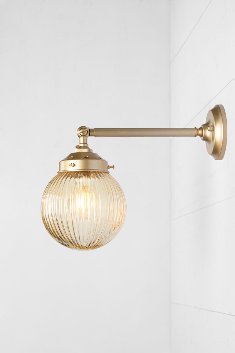 Amber glass reeded ball shade on a long gold/brass swivel straight arm.