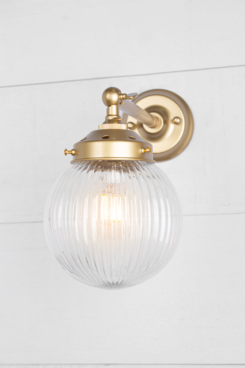 Clear glass reeded ball shade on a long gold/brass swivel straight arm.