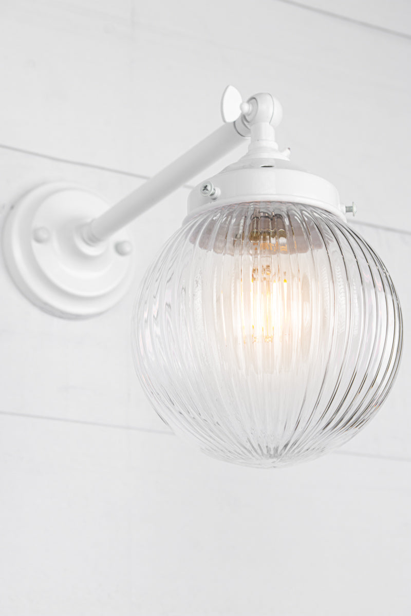 Clear glass reeded ball shade on a long white swivel straight arm.