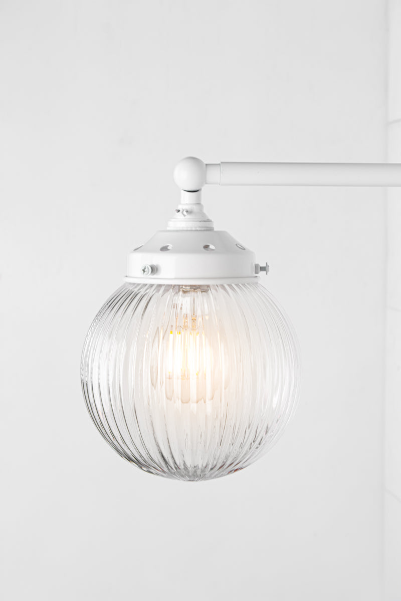 Close up of Clear glass reeded ball shade on a long white swivel straight arm.