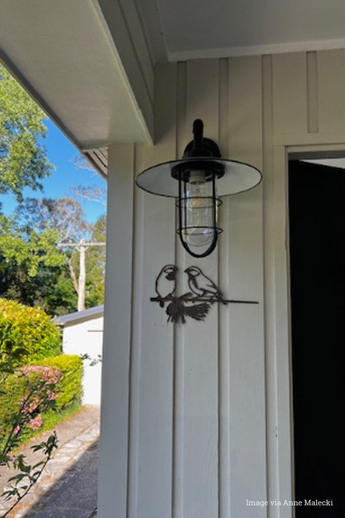 Black gooseneck outdoor wall light with clear glass and a black shade and cage. 