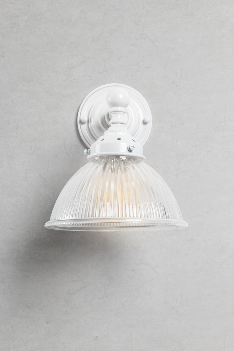 Front view of the White brass short straight arm fixture with a como shade. 