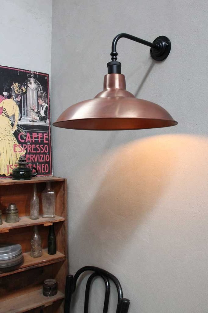 Black 90 degree wall sconce with a solid copper shade in a sitting nook.