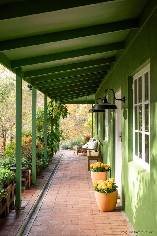 Two Smokehouse lights installed undercover of a green house with white door. 