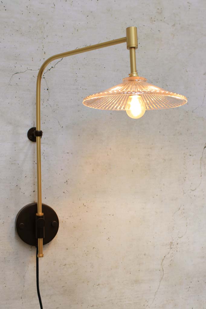 wing arm in gold brass with a wall plug and glass pleated shade.