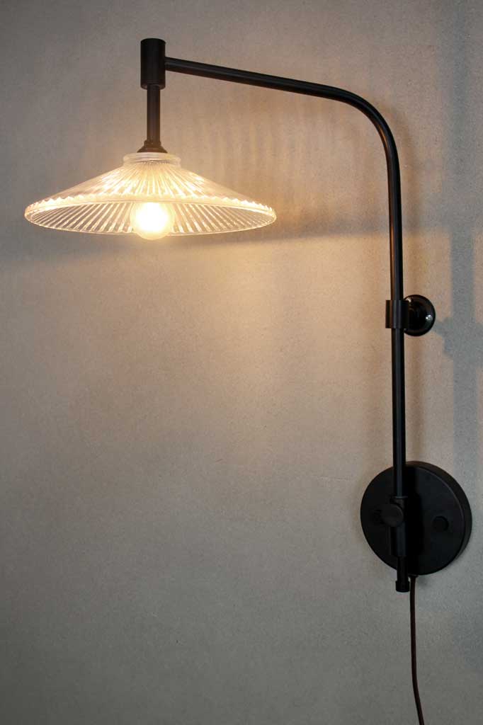 wing arm in black with a wall plug and glass pleated shade.