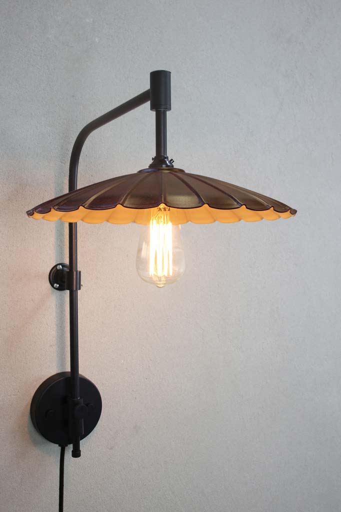 Black wing arm with wall plug and a large rust coloured umbrella shade