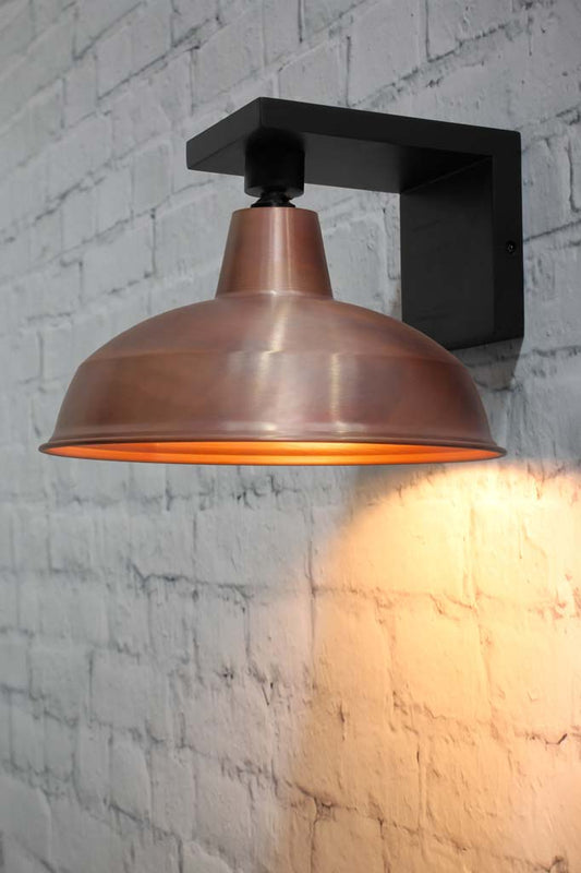 Copper warehouse shade on a black timber 90 degrees angled wall sconce.