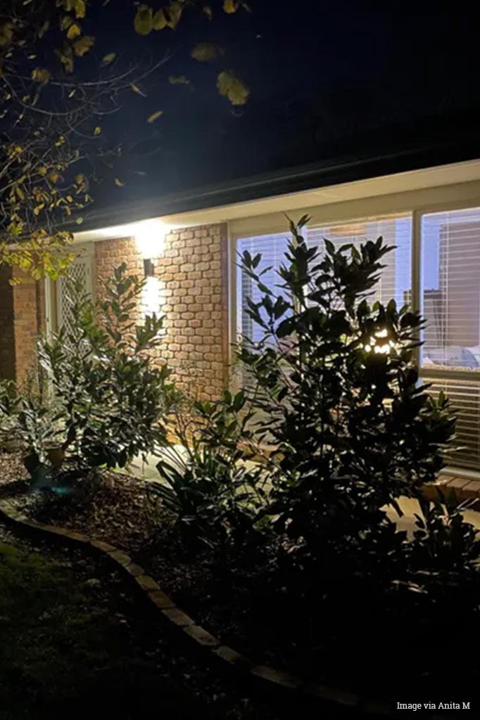 Black up/down outdoor spotlight installed on a brick façade. 