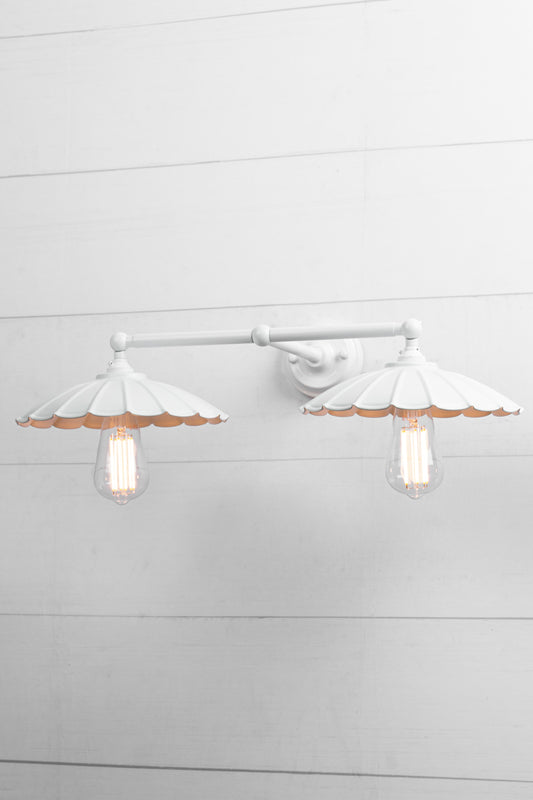 White umbrella shades on a white double arm wall sconce with a tilted view