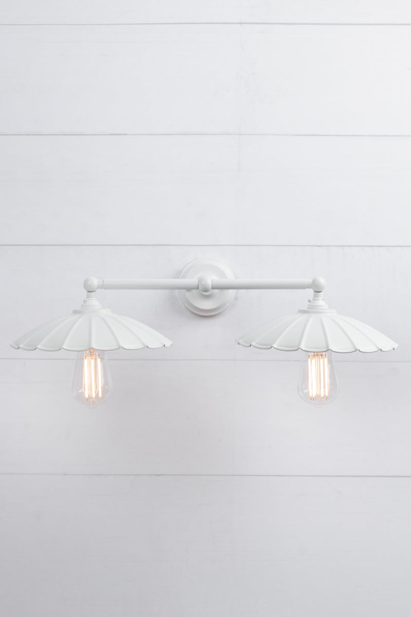 White umbrella shades on a white double arm wall sconce